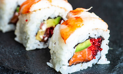 Sushi Set sashimi and sushi rolls served on stone slate