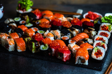 Sushi Set sashimi and sushi rolls served on stone slate
