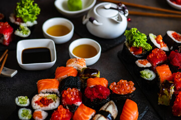 Sushi Set sashimi and sushi rolls served on stone slate