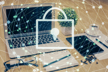 Double exposure of desktop with computer and lock icon hologram. Concept of data safety.