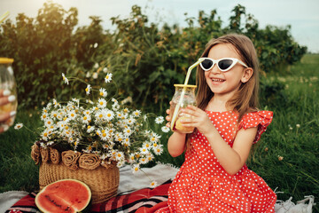 Fototapeta premium Beautiful Young Girl Dressed in Red Polka Dot Dress, Having Fun Time on a Picnic in the Field, Childhood Concept