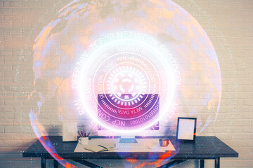 Computer on desktop in office with technology theme hologram. Double exposure. Tech concept.