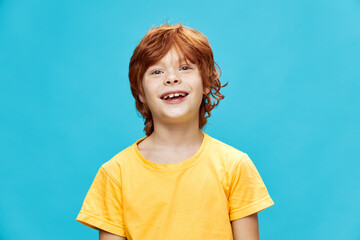 Happy child with red hair laughs on an isolated blue background 