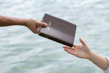 Man hand giving the Bible to women.Concept of giving