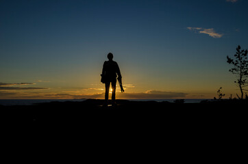 A man with a camera on the background of the sunset. Journey
