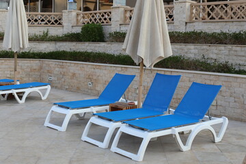 Comfortable blue and white deck chairs at the resort. Beautiful landscape with the sun lounger.