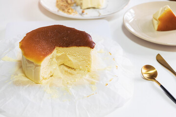 Basque Burnt Cheesecake on plate with piece of cake on white table background. 