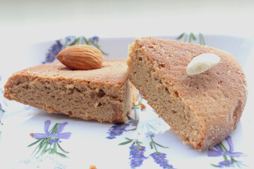 Indian home baked egg less spongy floor and coffee flavored cake called atta cake garnished with almond, cashew and Arabian dates in a lavender white plate