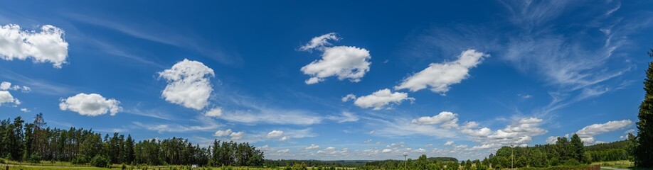 panorama white fluffy clouds on blue sky over foresty landscape
