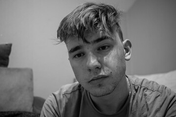 Fototapeta premium Young male with light brown hair looking interested in what the other person is talking to him in a green bedroom