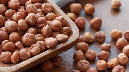 Hazelnut kernels and whole hazelnuts on old brown table, selective focus.