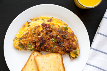 Homemade Denver Omelette on a white plate on a black background, top view. Flat lay, overhead, from above.