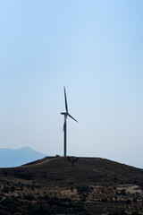 Fototapeta na wymiar Wind turbines on beautiful sunny summer autumn mountain landsape. Curvy road through mountain. Green ecological power energy generation. Wind farm eco field.