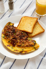 Homemade Denver Omelette on a white plate on cloth, low angle view.