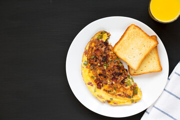 Homemade Denver Omelette on a white plate on a black background, top view. Flat lay, overhead, from above. Copy space.