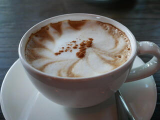 coffee with milk in white cup on wooden table in cafe.