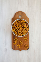 Crispy Pretzel Crackers in a Gray Bowl on a white wooden surface, top view. Flat lay, overhead, from above.