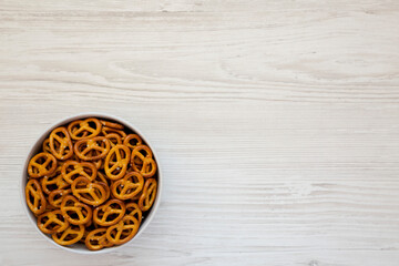 Crispy Pretzel Crackers in a Gray Bowl on a white wooden surface, top view. Flat lay, overhead, from above. Copy space.