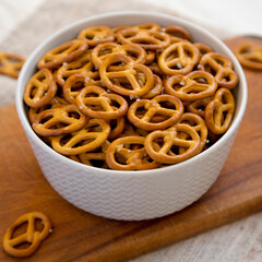 Crispy Pretzel Crackers in a Gray Bowl on a rustic wooden board, low angle view.