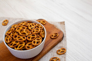 Crispy Pretzel Crackers in a Gray Bowl on a white wooden surface, side view.