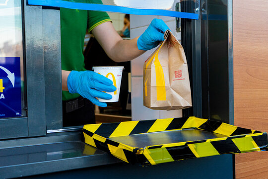McDonalds service the Drive-Thru due to coronavirus. Employee in gloves, order in window. Contactless transfer.