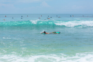 The guy is swimming on the surf board on the ocean. Healthy active lifestyle in summer vocation.