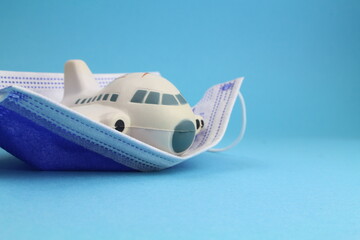 kleines Flugzeugmodel mit Schutzmaske und blauem Hintergrund steht für Reisen in Zeiten einer...