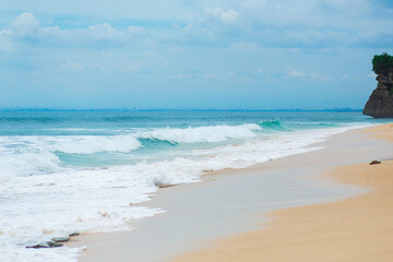 Fototapeta na wymiar An ideal tropical sandy beach for surfing on the ocean. Beautiful clear turquoise water and waves.
