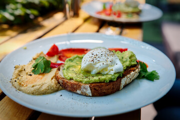 Avocado Sandwich with Poached Egg - guacamole and egg on toasted bread with hummus for healthy breakfast or snack