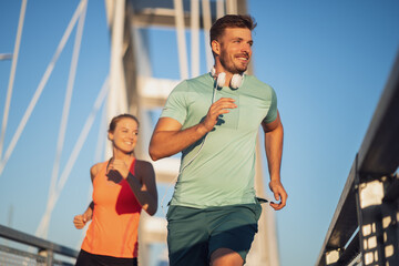 Young couple is jogging on bridge in the city.