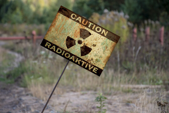 A sign stuck in the ground with the words: caution, radiation, at an angle. Warning sign in an infected area of radioactive danger.