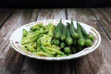 Pile of boiled or steamed green Sesbania(Grandiflora) and fresh okra (green roselle) on the plate. Famous side dish vegetable served with shrimp paste in Asia restaurant. 