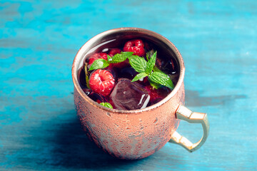 Raspberry and mint cocktail in copper mug (variation of Moscow mule) on the rustic background. Selective focus. Shallow depth of field.