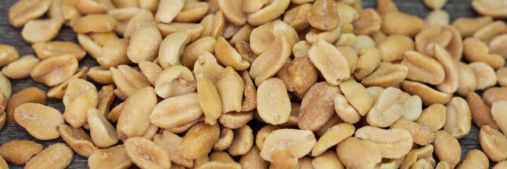 Peanuts close-up. Lots of peanuts on the wooden table. Banner