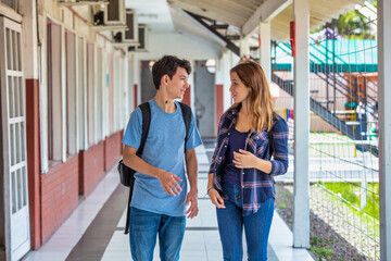 Two caucasian teenagers friends happy returning to school speaking along the hallway. Back to school concept