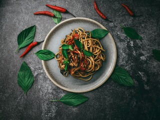Hot and spicy Spaghetti with chicken top view,Chicken spaghetti pasta over black stone background with copy space, italian food. Stir Fried Spicy Spaghetti with Chicken in dark tone.