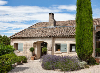 Fototapeta na wymiar A house with a tiled roof and lavender with cypress is a typical picture in Provence, France