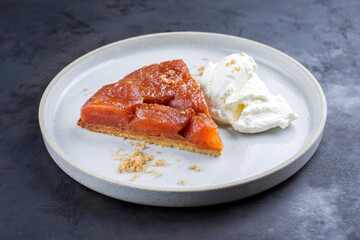 Traditionelle französische Tarte Tatin mit Äpfel und Eis Creme angeboten als close-up auf einem Modern Nordic Design Teller mit rustikalen Hintergrund