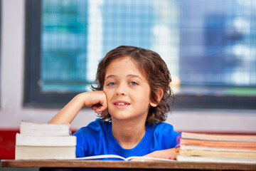 Happy caucasian boy in the classroom thinking. Back to school concept