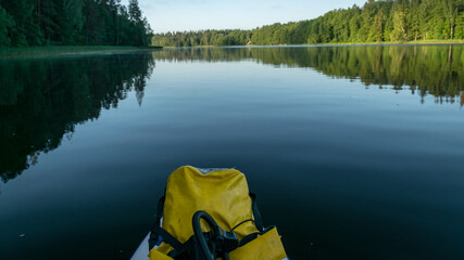 mirror image on the lake, green forest by the lake in reflection in the blue water, sup board in...