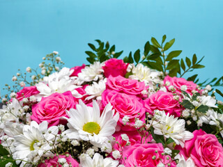 Beautiful pink roses and white daisies in a box on a blue background.