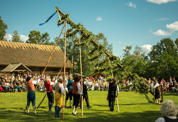 Raising of a midsummer pole duringa a traditional celebration of swedish midsummer in the small town of Skara - obrazy, fototapety, plakaty