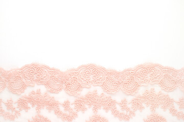 Openwork lace on a white background. Pink delicate lace close-up. Openwork fabric for sewing. Lace textiles. Fabric for sewing and design. There is space for text.