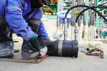 Worker is using a hydraulic press to squeeze the coupler to connect the rebar in construction site.