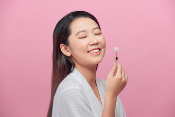 Close up of young woman with rose quartz face roller. She is doing beauty facial massage therapy