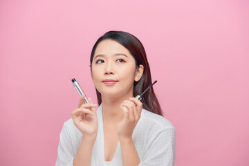 Obraz premium Pretty lady smiling isolated on pink background hold mascara in hands