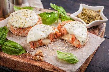 Salmon cutlets with cheese, walnuts, pesto and basil on a wooden cutting board. Delicious and healthy seafood dishes. Cooking like in a restaurant