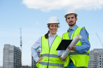 Two Young Engineers Man and Woman In Green Vests And Helmets
