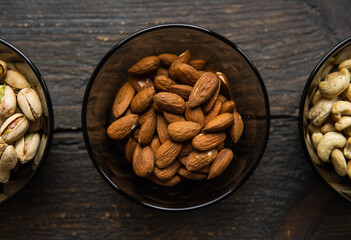 Almond, pistachio and cashew in a small plates which standing on a black table. Nuts is a healthy vegetarian protein and nutritious food.