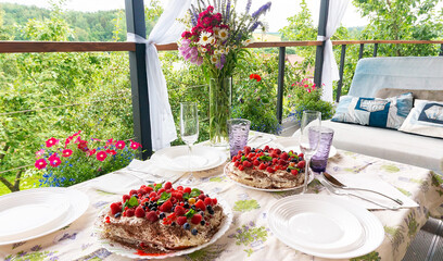 A set table with glasses, plates, napkins, silverware, colored glasses on a summer terrace outside the city. Summer dinner on the garden terrace outside the city with a bouquet of wildflowers.
